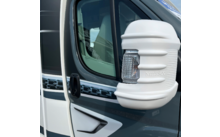 Rétroviseur avec coque blanche et clignotant intégré sur un véhicule gris; vitre et poignée de porte visibles