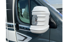 Rétroviseur avec coque blanche et clignotant intégré sur un véhicule gris; vitre et poignée de porte visibles