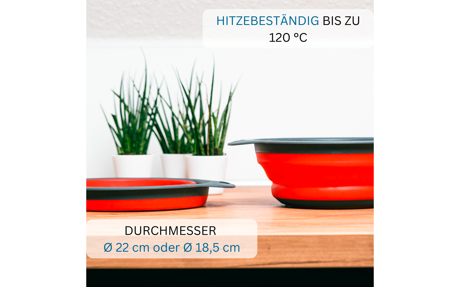 Eine zusammengeklappte und eine aufgeklappte rote Schale mit grauem Rand auf einer Holzfläche; zwei weiße Pflanztöpfe mit grünen Gräsern im Hintergrund; sichtbarer Text: 'HITZEBESTÄNDIG BIS ZU 120 °C' und 'DURCHMESSER Ø 22 cm oder Ø 18,5 cm'