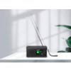 Schwarzes Radio auf weißem Tisch, ausgezogene Antenne mit Markierung "360mm", Lautsprechergitter, Display und Drehknopf; Fenstergitter-Schatten auf weißer Wand; rechts grüne Pflanze