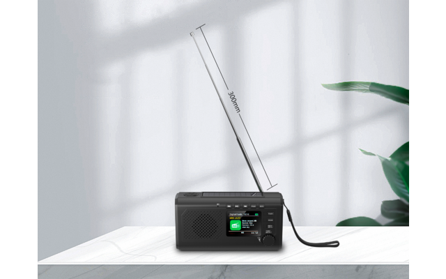 Schwarzes Radio auf weißem Tisch, ausgezogene Antenne mit Markierung "360mm", Lautsprechergitter, Display und Drehknopf; Fenstergitter-Schatten auf weißer Wand; rechts grüne Pflanze
