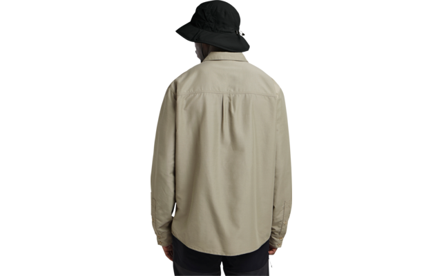 Person von hinten, trägt beige Hemdjacke, schwarzen breitkrempigen Hut und dunkle Hose