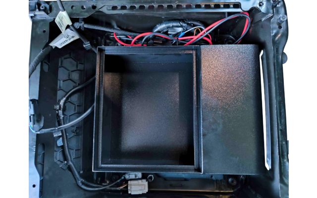 Offenes Gerätegehäuse mit einem leeren quadratischen Metallbehälter in der Mitte, sichtbaren roten und schwarzen Kabeln, Steckverbindern und Gehäusekanten