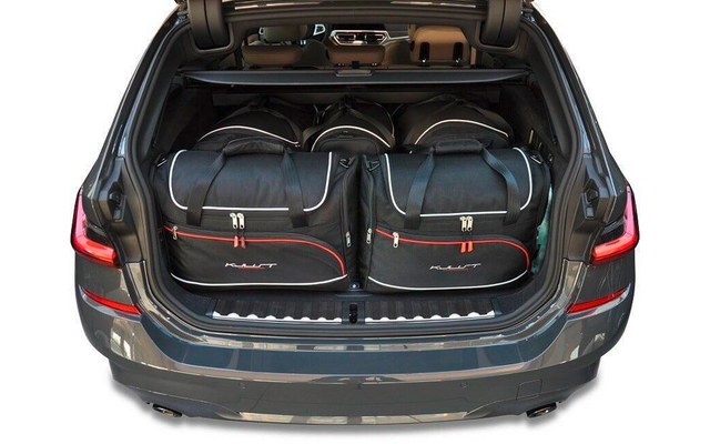 Geöffneter Kofferraum eines Autos mit zwei schwarzen Reisetaschen mit roten Akzenten nebeneinander