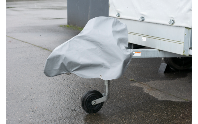 Graue Abdeckung über Stützrad eines Anhängers; Rad sichtbar, weiße Plane und nasser Asphalt