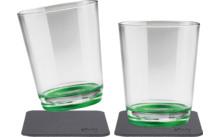 Two transparent glasses with green bases, one standing and the other tilted, both on gray coasters