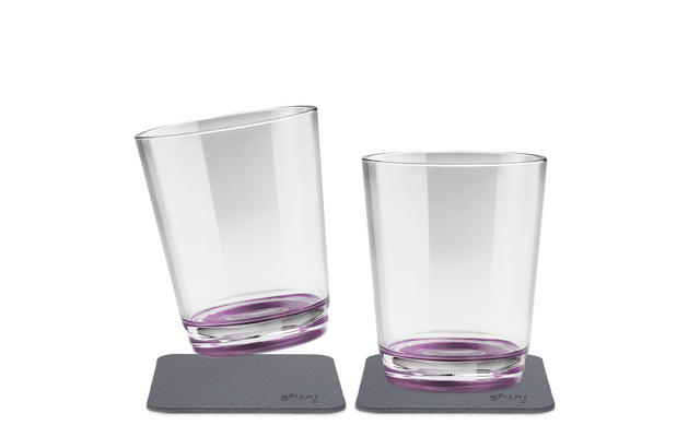 Zwei durchsichtige Trinkgläser mit violett getöntem Boden auf zwei quadratischen grauen Untersetzern; ein Glas leicht geneigt