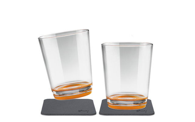 Zwei transparente Gläser mit orangem Boden auf grauen Untersetzern, eines leicht geneigt