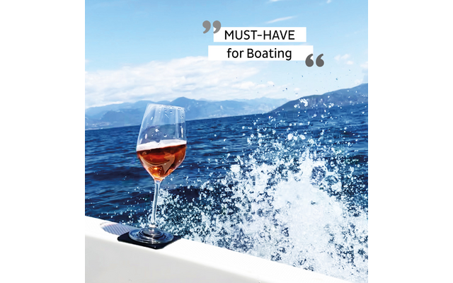 Weinglas mit rosa Wein auf der Reling eines Bootes mit Meer und Wellen im Hintergrund