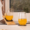 Deux verres de jus d'orange sur un plan de travail de cuisine clair, un verre incliné par un support en bois