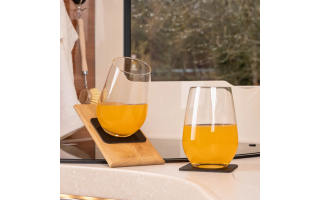 Deux verres de jus d'orange sur un plan de travail de cuisine clair, un verre incliné par un support en bois
