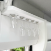 Five hanging wine glasses under a white cabinet