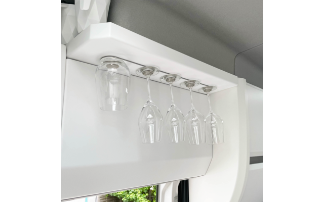 Five hanging wine glasses under a white cabinet