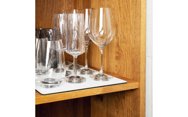 Verschiedene Glasarten, darunter Weingläser und Wassergläser, stehen auf einem weißen Tablett in einem Holzregal