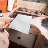 Eine Person schneidet mit einer Schere ein weißes Blatt Papier auf einer Küchenarbeitsplatte
