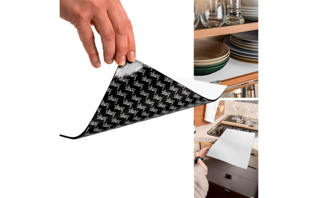 Main retirant un film protecteur d'un tablier blanc rectangulaire, armoires de cuisine et vaisselle en arrière-plan