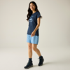 Personne aux longs cheveux foncés, t‑shirt bleu marine avec impression blanche, short bleu clair, chaussures de randonnée foncées et chaussettes foncées, fond uni clair