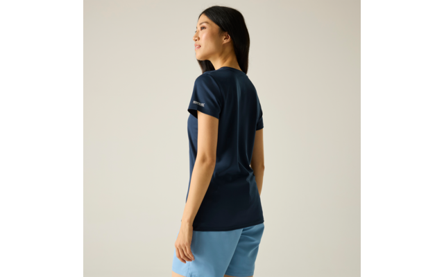 Personne en profil trois-quarts vers la gauche, T-shirt bleu foncé, short bleu clair, fond uni clair