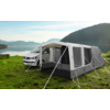 Campingplatz mit einem weißen Wohnmobil und einem grauen Vorzelt am See, umgeben von Bergen
