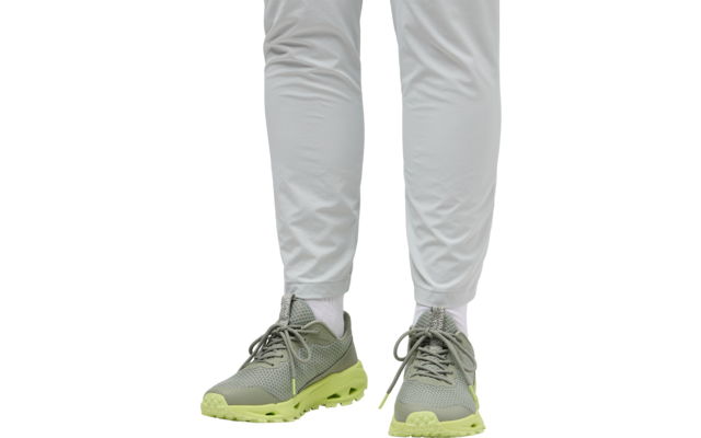 Beine einer Person mit weißen Hosen und grauen Sportschuhen mit gelben Sohlen