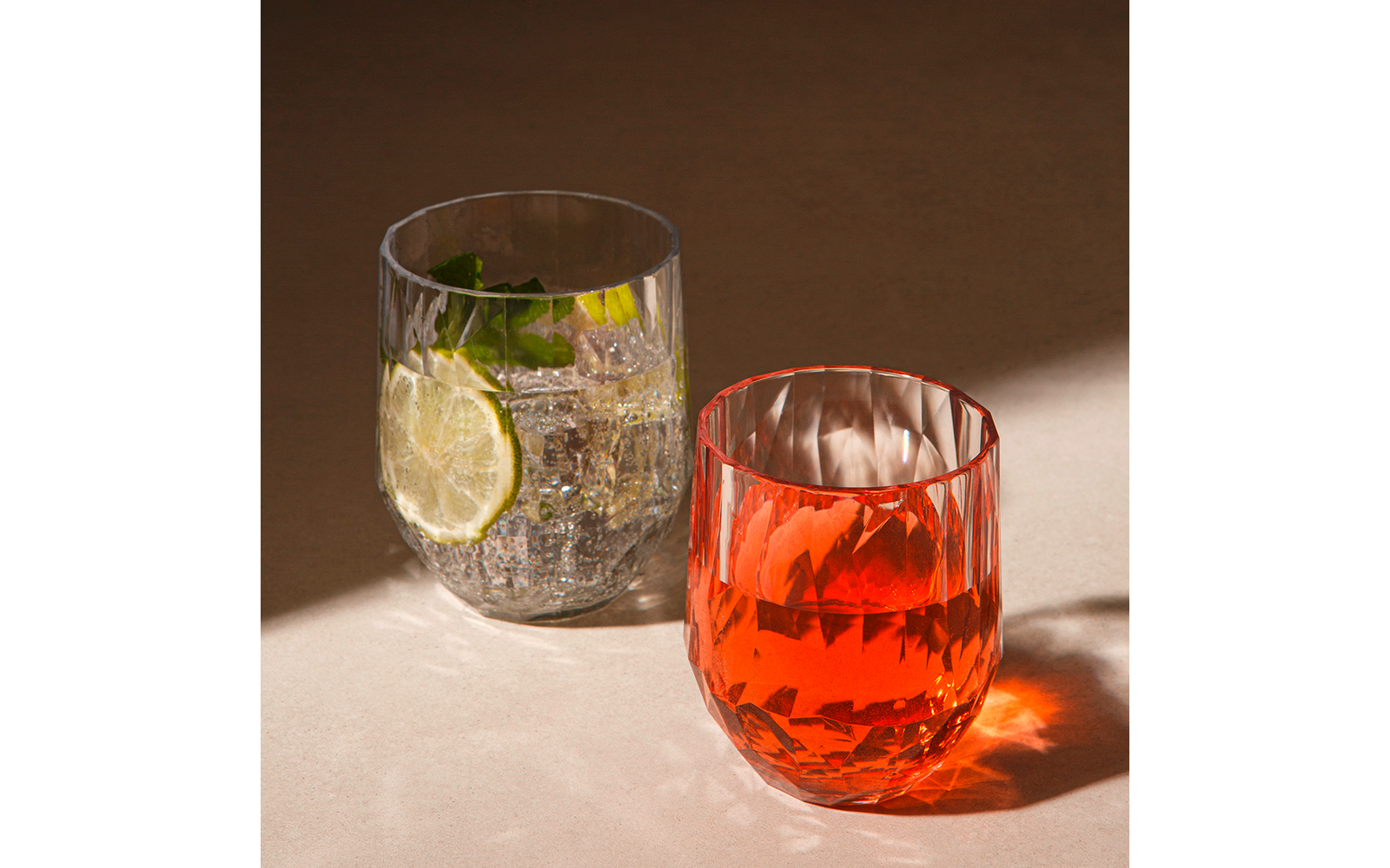 Zwei Gläser mit Getränken, eines mit klarem Wasser, Zitrone und Minze, das andere mit rotem Getränk