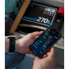 Main tenant un smartphone avec une application, balance électronique affichant 270 kg en arrière-plan