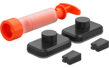Orange transparent cylindrical object with a lever, two black rectangular bases with round knobs and two small black rectangular inserts on a white background