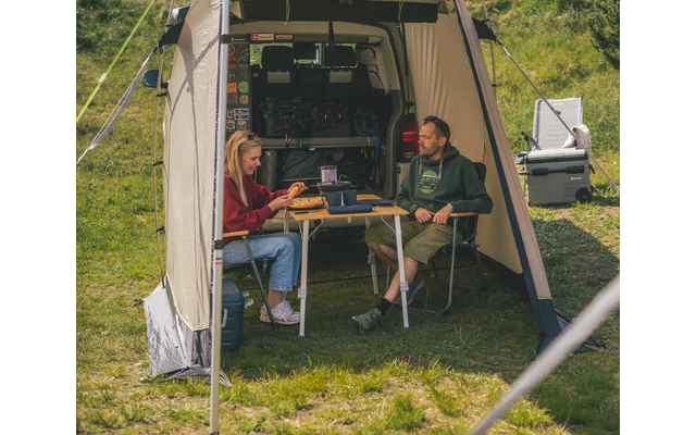 Zwei Männer sitzen an einem Klapptisch vor einem Wohnwagen im Freien