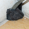 Schep met zwart zand of aarde in een hoek van een kamer op een lichte vloer