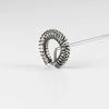 Ringförmige Metallspirale an einem dünnen Metallstab vor weißem Hintergrund