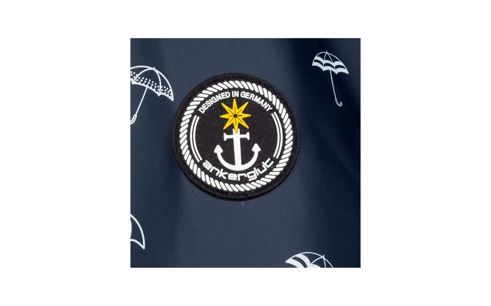 Ronde zwarte patch met wit anker, gele ster, witte tekst 'DESIGNED IN GERMANY' en touwrand op donkerblauwe achtergrond met witte paraplu-icoontjes