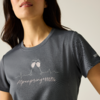 Haut du corps d'une personne portant un t‑shirt gris à encolure ronde, imprimé de deux verres qui s'entrechoquent, motif de ligne de battement cardiaque et inscription "Alpenprinzessin", petit logo sur la manche
