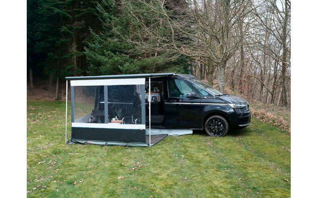 Schwarzer Van mit geöffneter Seitentür und angebautem Vorzelt mit transparenter Front, steht auf Gras vor Bäumen