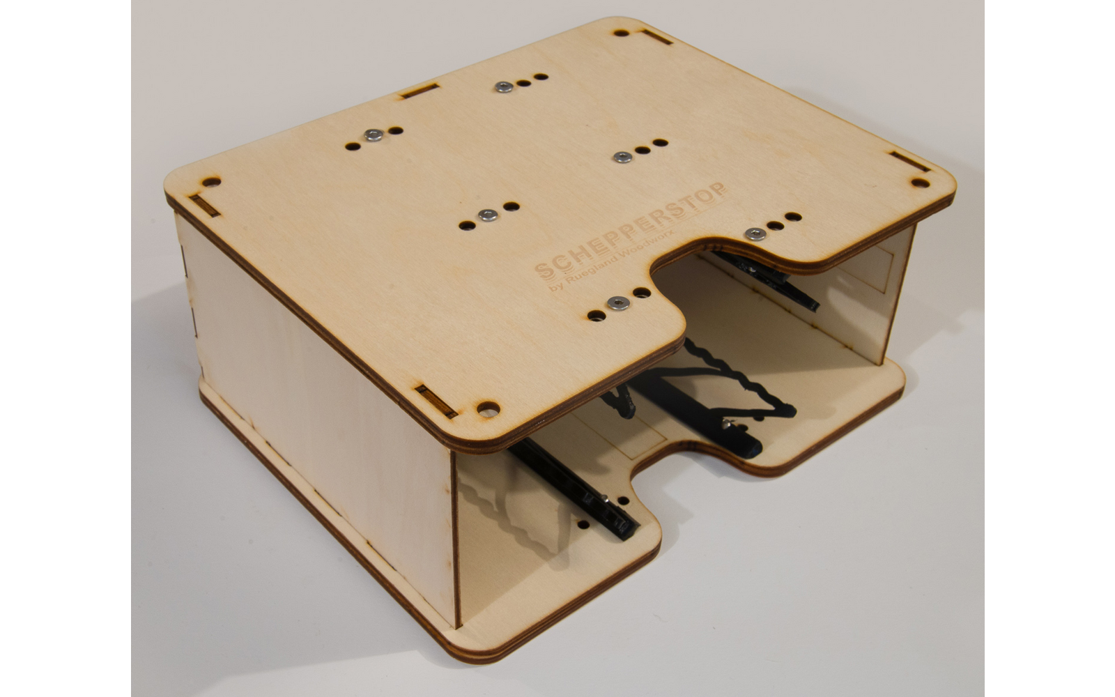 Rectangular flat plywood box with transparent side panels, cutouts, screws and a printed label on the top surface