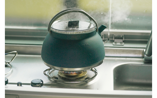 Zwarte waterkoker op fornuis met stoom uit tuit