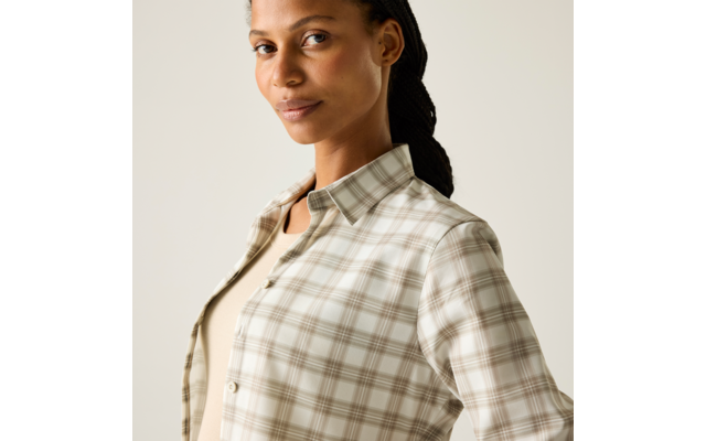 Person mit zurückgebundenem dunklem Haar, trägt karierte Hemdjacke über hellem Oberteil, Oberkörper sichtbar, Blick leicht zur Seite