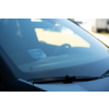 Pare-brise d'une voiture avec essuie-glace, un petit appareil bleu sur le tableau de bord à l'intérieur et le volant en arrière-plan