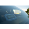 Appareil électronique bleu avec affichage numérique sur le tableau de bord d'une voiture, visible à travers le pare-brise