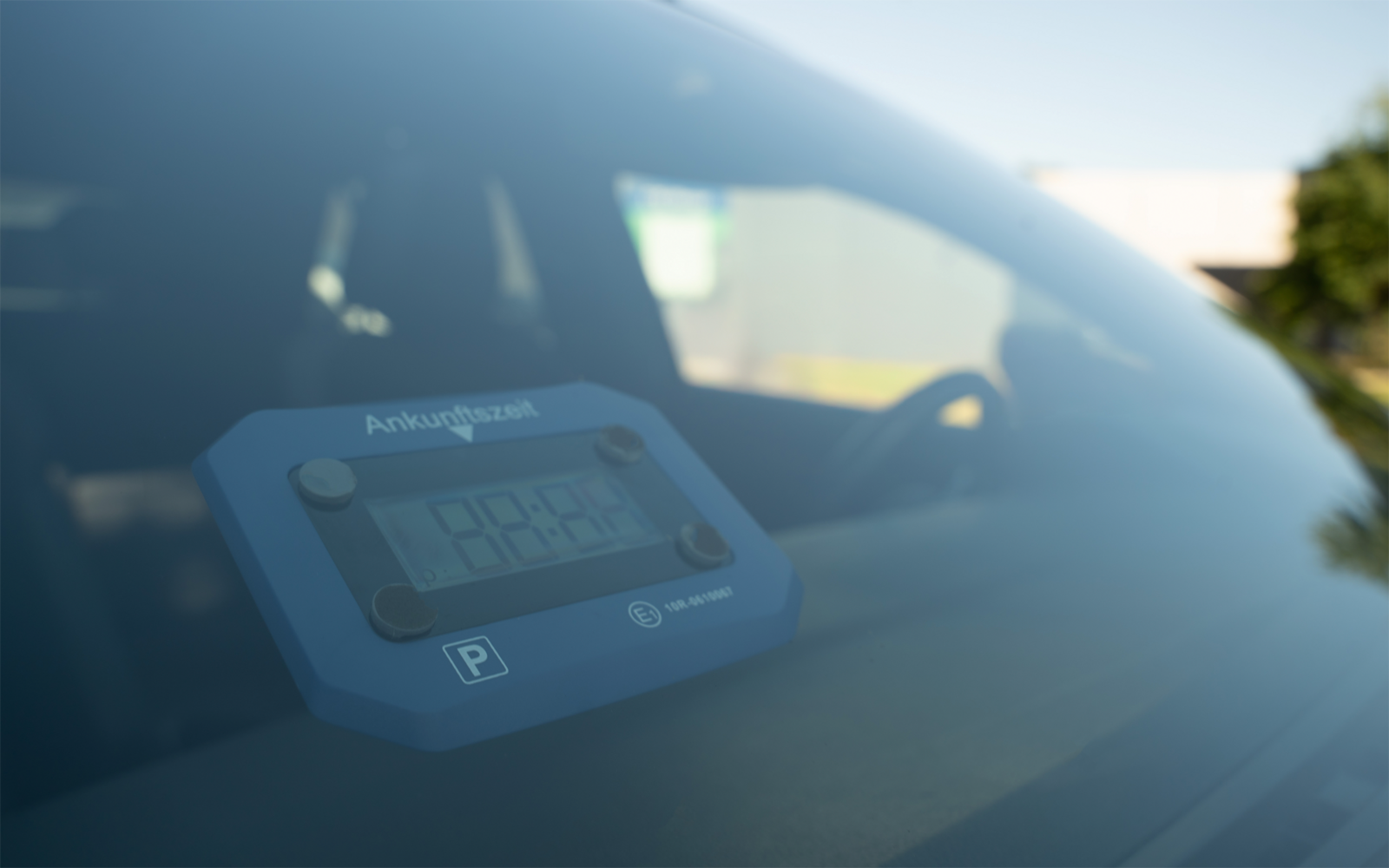 Appareil électronique bleu avec affichage numérique sur le tableau de bord d'une voiture, visible à travers le pare-brise