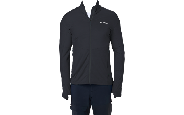 Person mit kurzem Haar steht frontal vor weißem Hintergrund, trägt schwarze, enganliegende Jacke mit Reißverschluss und kleinem weißen Logo auf der linken Brust, weißes T‑Shirt am Kragen sichtbar, dunkle Hose, Hände seitlich