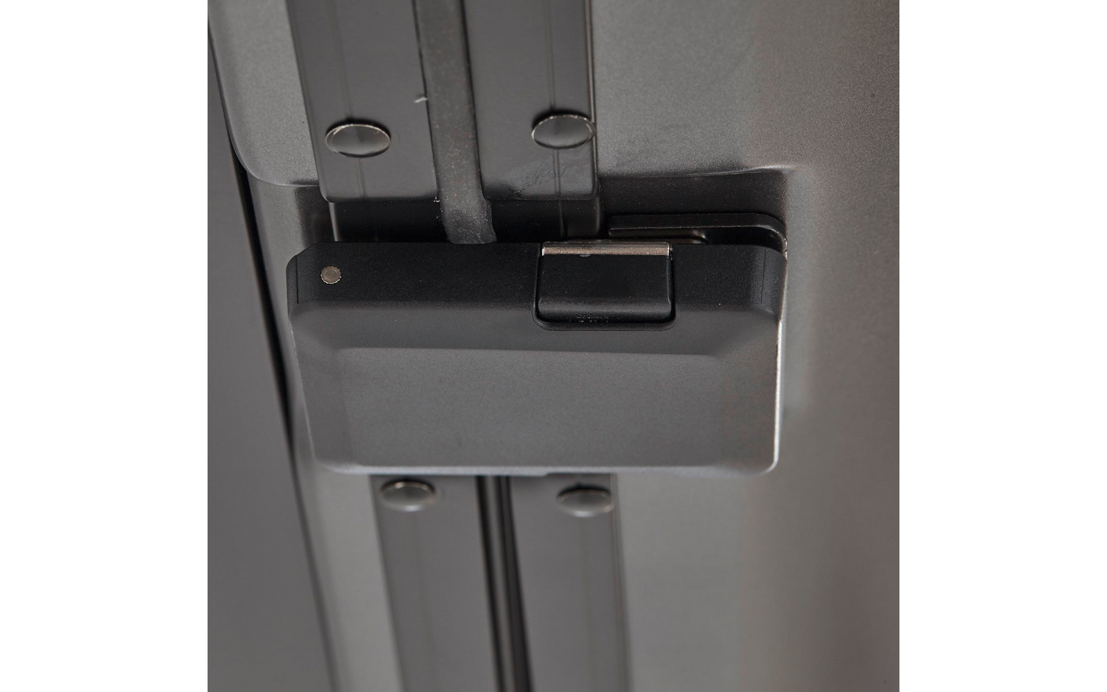 Nahaufnahme eines grauen Gehäuses mit kleinem rechteckigen Verschluss auf zwei silbernen Metallschienen, mehrere sichtbare Schraubenköpfe