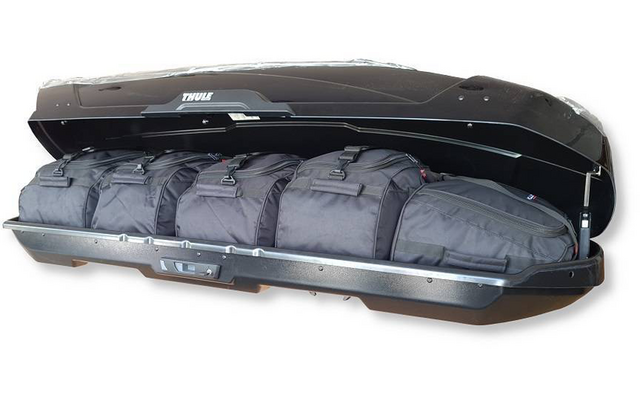 Coffre de toit noir ouvert contenant plusieurs sacs de voyage noirs
