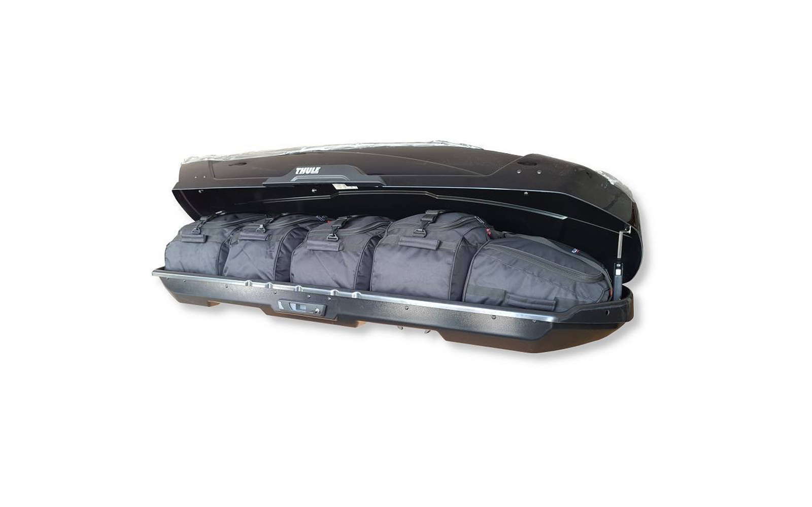 Coffre de toit noir ouvert contenant plusieurs sacs de voyage noirs