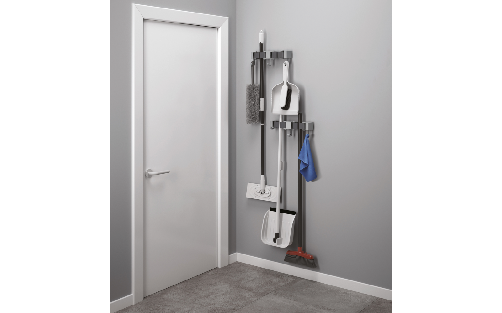 Weiße Tür links; rechts an grauer Wand eine Wandhalterung mit Besen mit roten Borsten, zwei weißen Schaufeln, Mopp, Bürste und blauem Tuch