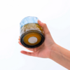 Hand hält ein Glas mit braunem Inhalt