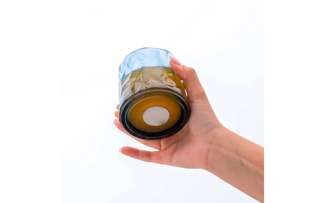 Hand hält ein Glas mit braunem Inhalt