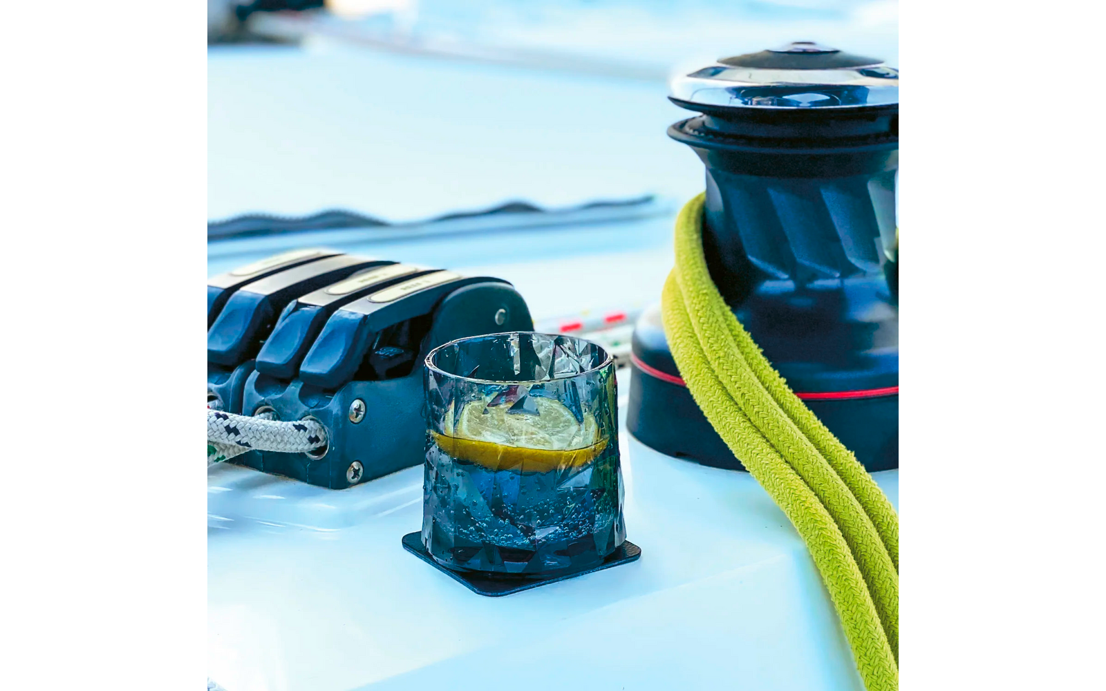 Glas mit Getränk auf Tisch neben gelbem Tau und schwarzem Bootszubehör