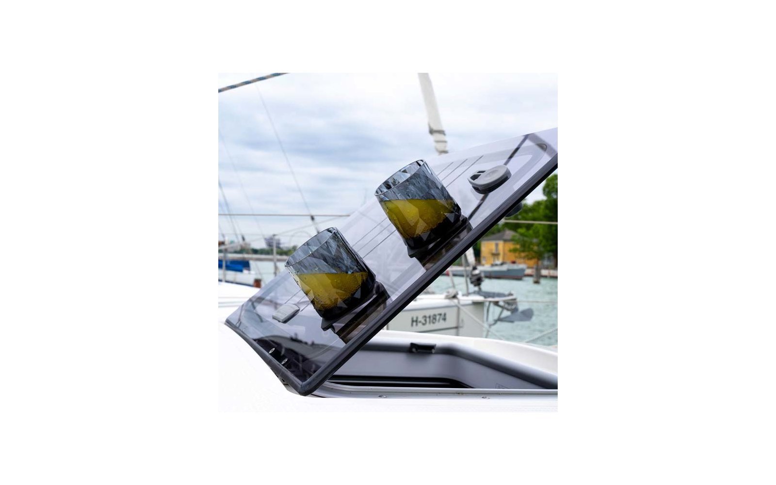 Tinted open boat hatch with two faceted cylindrical objects showing yellow and dark surfaces; water, boats and a dock in the background