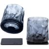 Two short smoky faceted glasses on a white background; one stands on a black square coaster, the other lies on its side on a second coaster