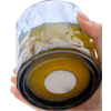 Hand holding an upside-down faceted drinking glass with a brown base and a white round mark on a white background